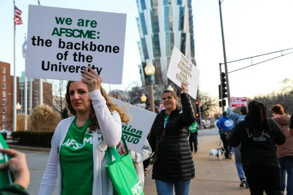 Woman on the picket line with a sign that says "We are AFSCME: The backbone of the university"