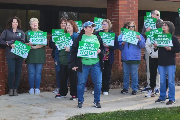 Workers holding signs that say Fair Contract Now.