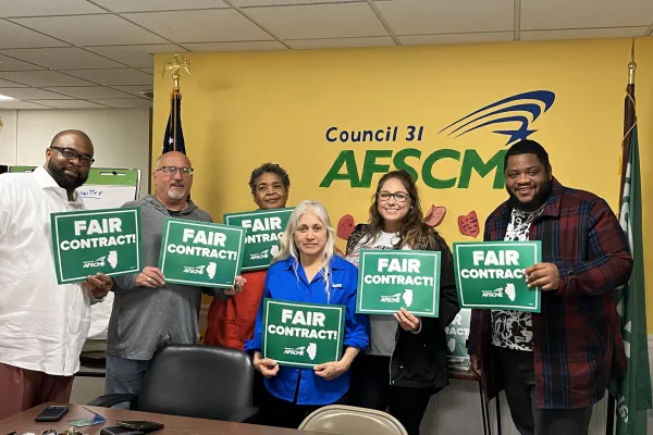 AFSCME members hold up Fair Contract signs with the state of Illinois outline on them.